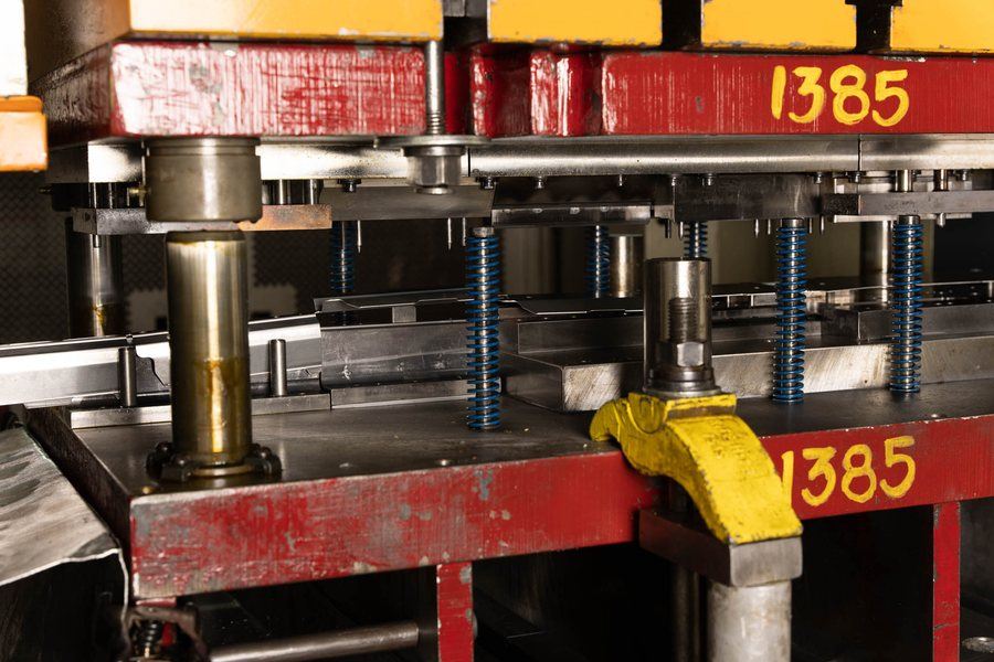 Detail of a die set in a press, showing guide pins and springs